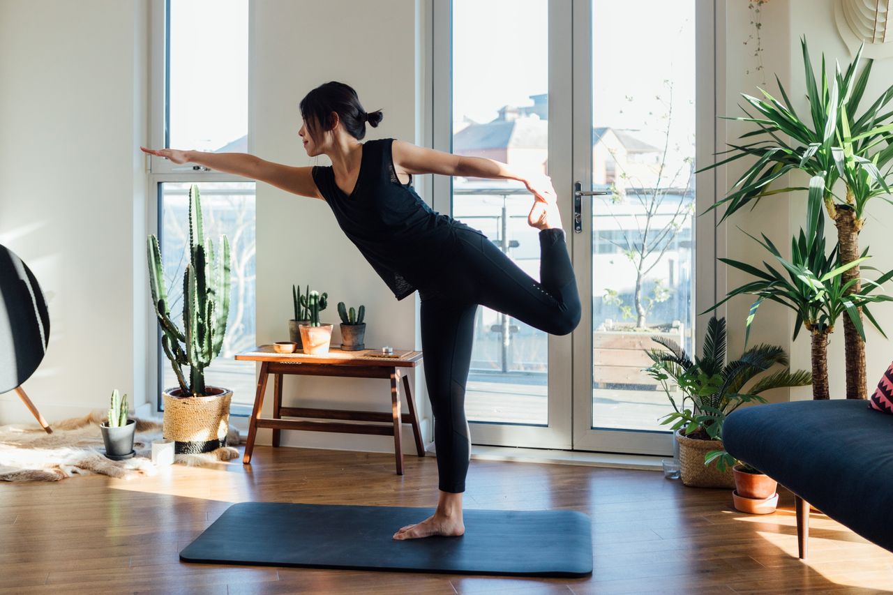 A woman practices yoga on a mat in her living room