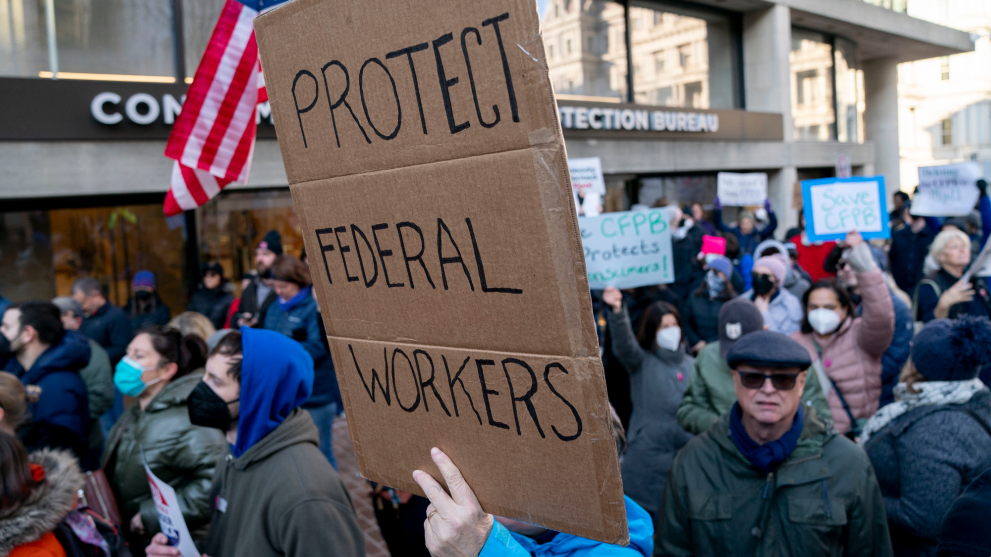 A demonstrator holds a "Protect Federal Workers" sign during a rally outside the US Consumer Financial Protection Bureau (CFPB) headquarters in Washington, DC, US, on Monday, Feb. 10, 2025. In another weekend takeover of a federal agency's operations, staffers from an efficiency initiative led by billionaire Elon Musk helped to effectively shut down the Consumer Financial Protection Bureau, as they gained access to an array of the bureau's protected information. Photographer: Stefani Reynolds/Bloomberg via Getty Images