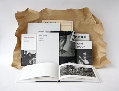 A variety of different sized books leaning against brown packaging paper.