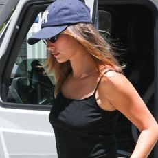 Hailey Bieber was spotted in West Hollywood wearing a black camisole, navy-blue Yankees hat, and white capri pants with heeled mule sandals. 