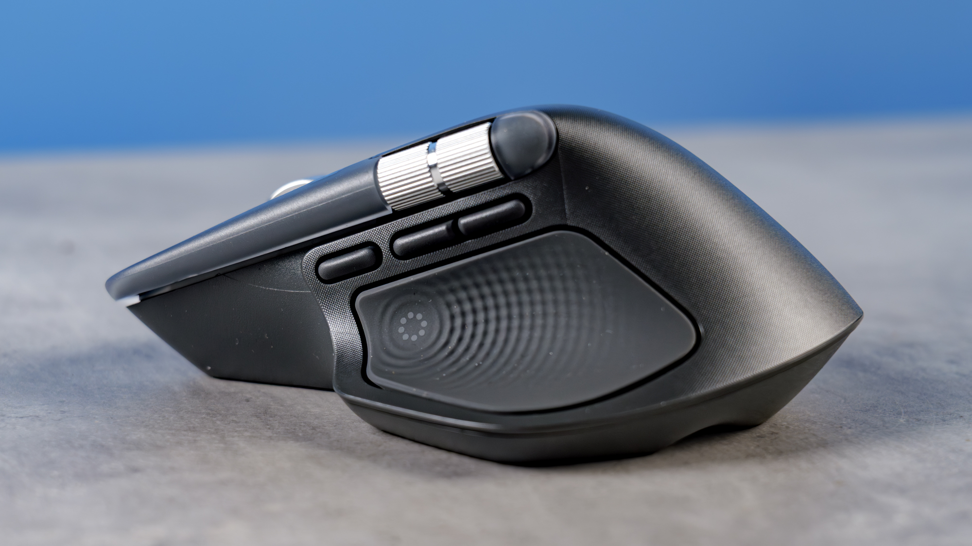 A photo of the Logitech MX Master 4 on a stone surface with a blue background