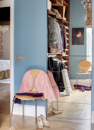 blue bedroom with mirror reflecting inside a walk in wardrobe