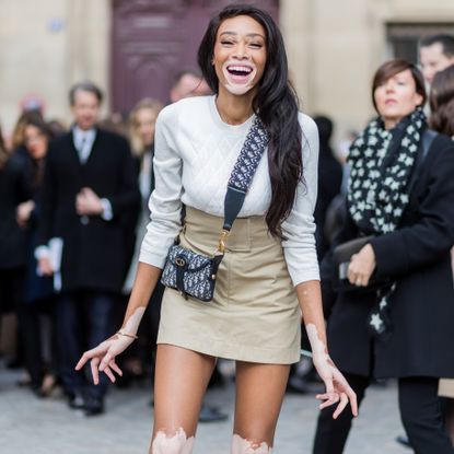 paris, france march 03 model winnie harlow wearing white knit, mini skirt, boots, dior bag outside dior on march 3, 2017 in paris, france photo by christian vieriggetty images