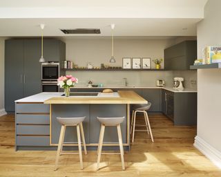 A square, medium kitchen island size with L-shaped breakfast bar and gray bar stools in a gray scheme with open shelving.