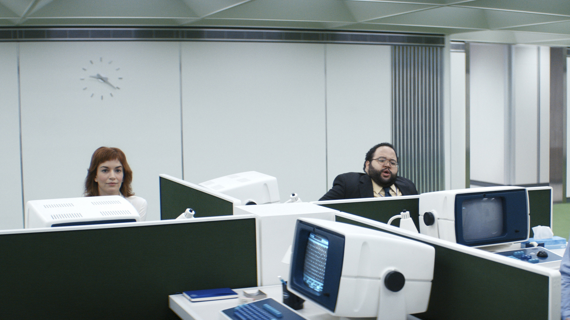Two Lumon Industries employees look up from their desks in Severance season 1