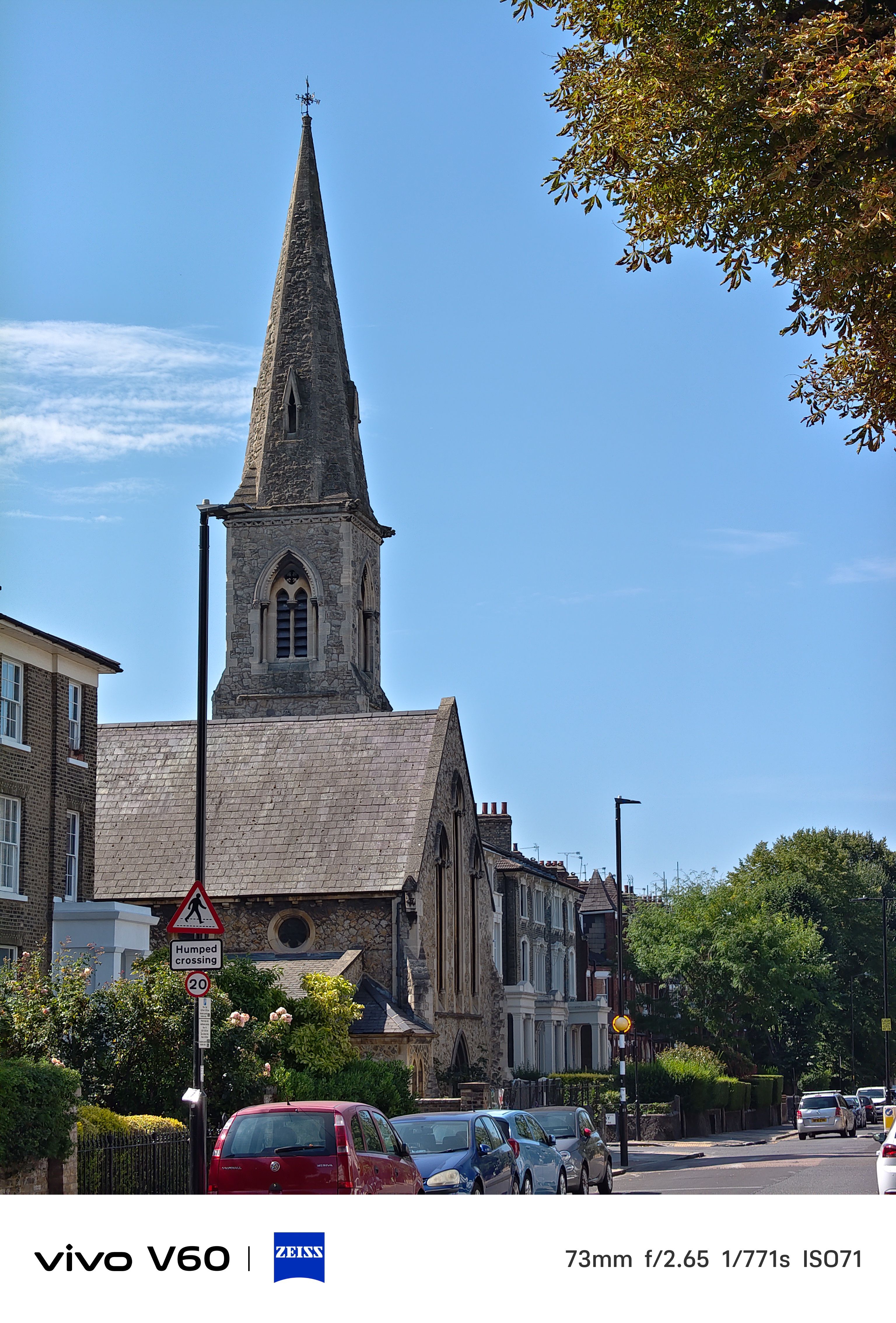 A street in London with a church with a tall spy in front of a blue sky