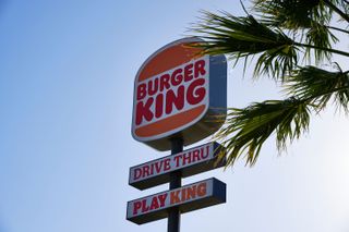 A Burger King drive thru sign next to a palm tree