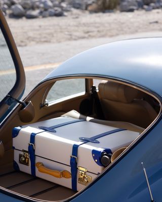 globe trotter suitcase in back on blue classic car in palm springs