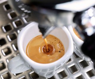 An espresso machine brewing a shot of coffee into a white mug
