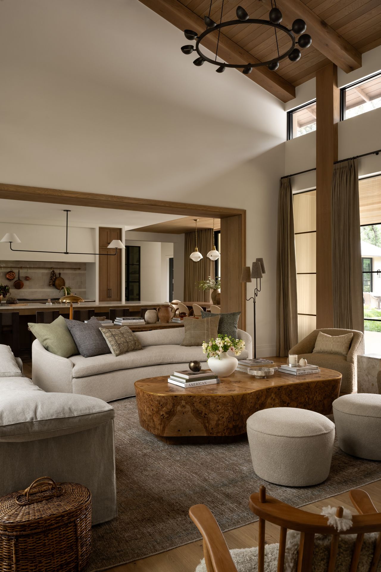 An open layout living room mixes a range of seating, from individual upholstered stools to two separate sofas, all around a burl wood coffee table