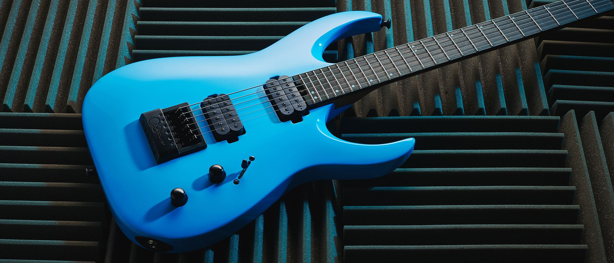 A Jackson Pro Plus Series Signature Misha Mansoor Juggernaut ET6 guitar lying on some acoustic foam