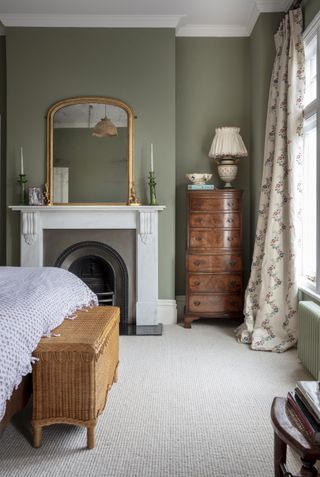 green bedroom with a period fireplace