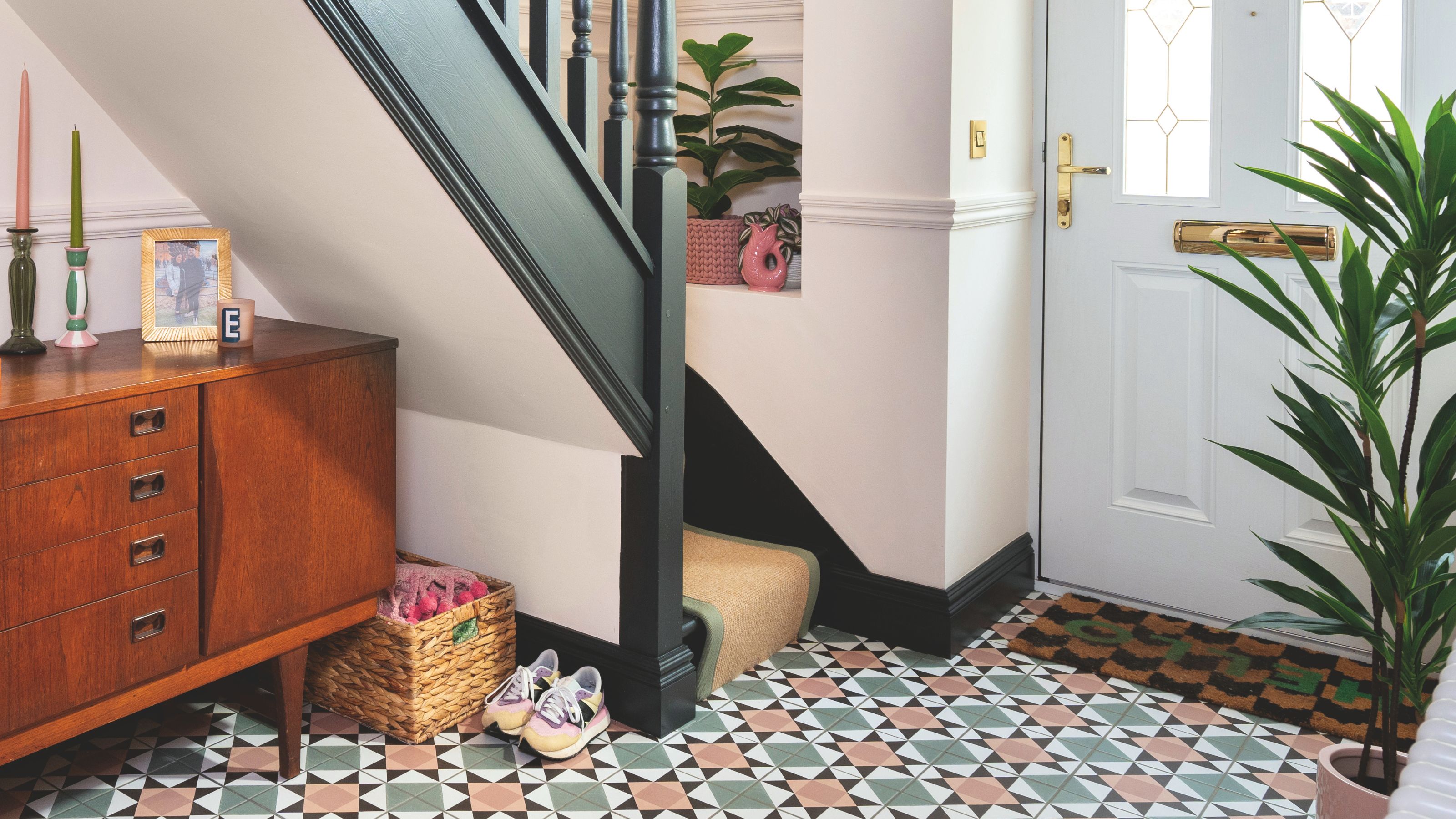 Hallway with patterned floor tiles and a wooden cabinet, with stairs going up to the upper floor