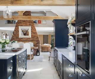 A large open-plan space with a Shaker-style kitchen in navy blue with white stone worktops