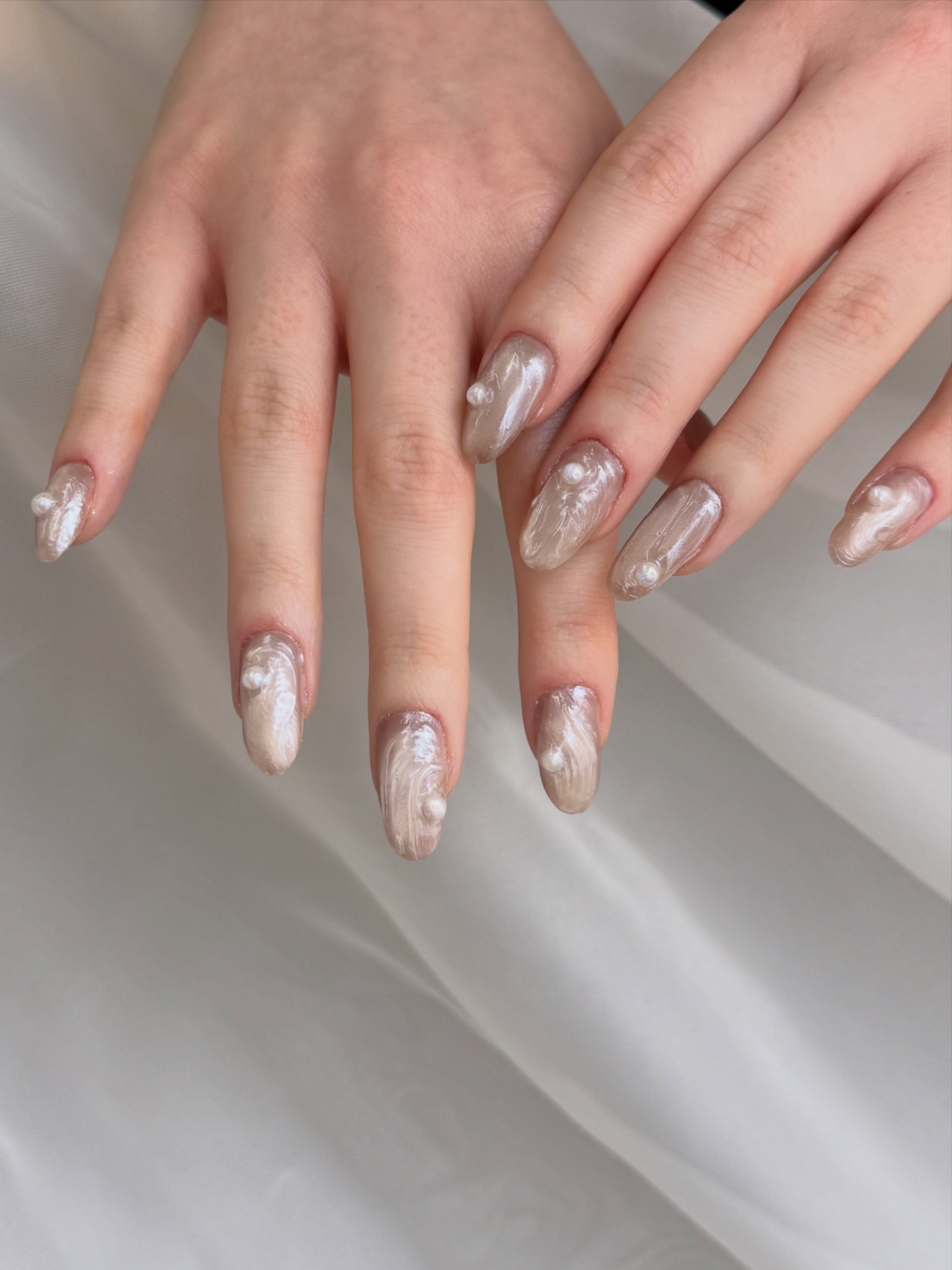 Almond-shaped nails with ivory oyster shell swirls and small raised pearl accents