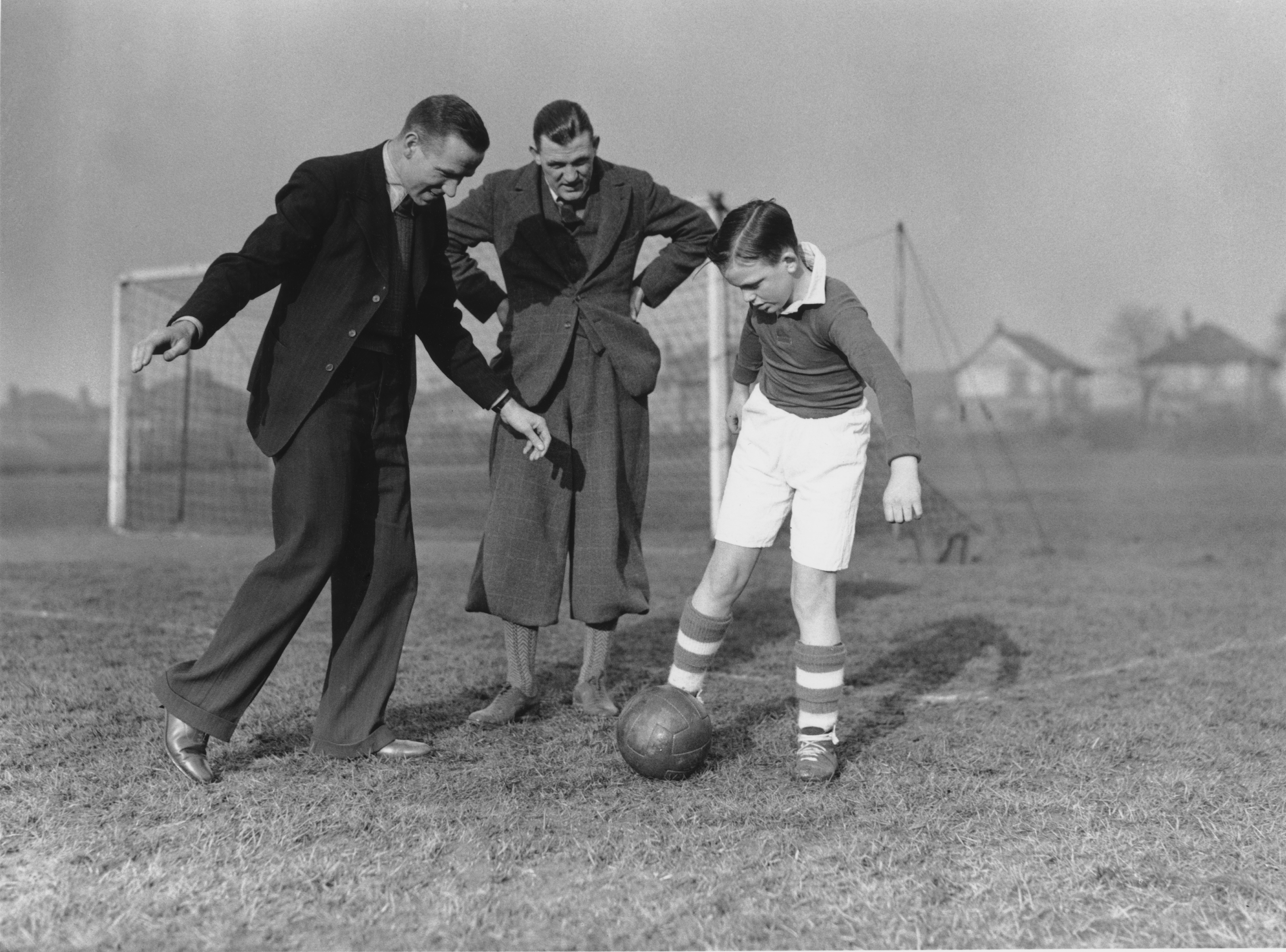 Liverpool player Matt Busby (left) gives some advice to youngster Len Langford (right) while his father, the Manchester City goalkeeper also named Len Langford, watches on.