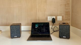 Ruark MR1 Mk3 powered speakers either side of a laptop, on a white surface