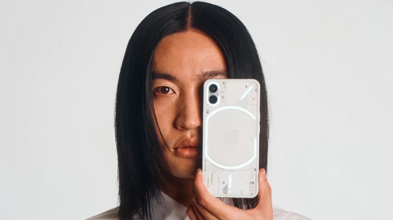 The Nothing Phone (1) from the back in white, next to someone's face