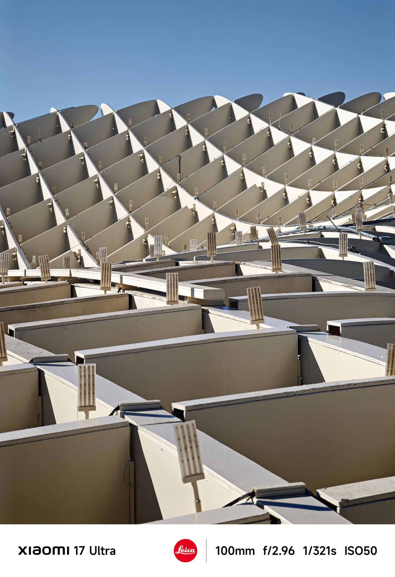 Abstract view of a modern geometric structure with repeating triangular panels under a clear sky.