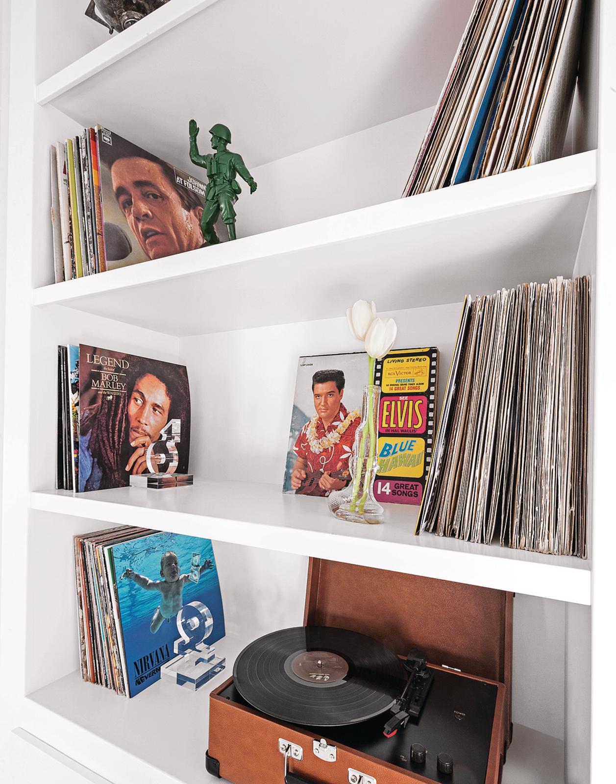 Close-up image of a white shelving unit that is decorated with lots of vinyl records and a record player.