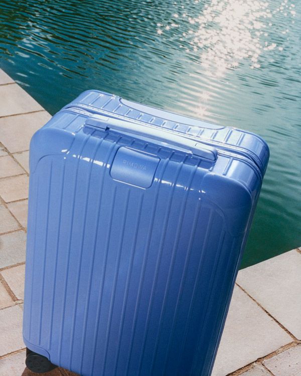 A sea blue minimalist cabin suitacase is captured in multiple sun-lit settings.