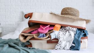 Open suitcase on a bed filled with holiday clothes