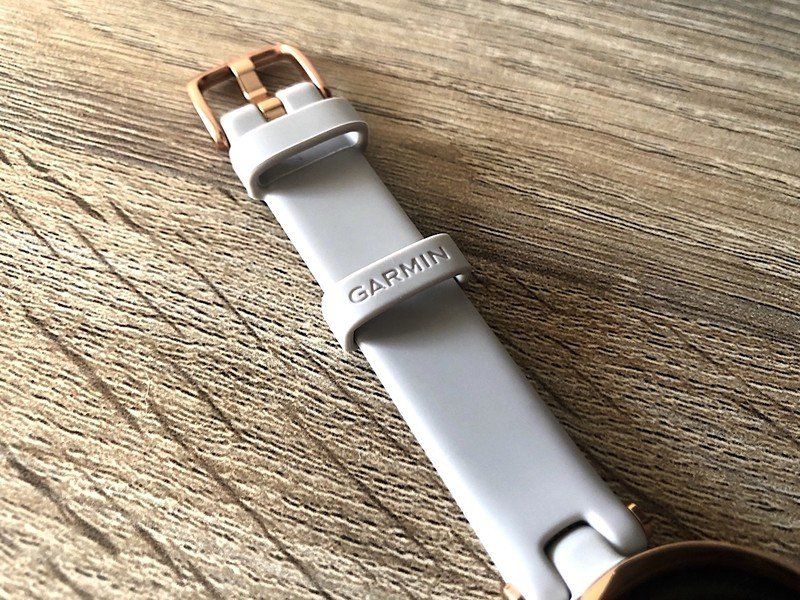Garmin Lily smartwatch band laid out on a wooden table.