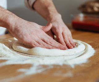 High angle view of an anonymous chef making homemade pizza dough on a kitchen table