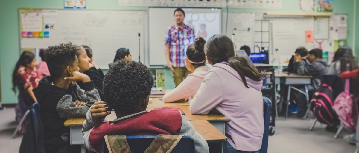 Classroom with students at a desk looking at a teacher