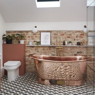 bathroom with exposed brick walls and copper bathtub