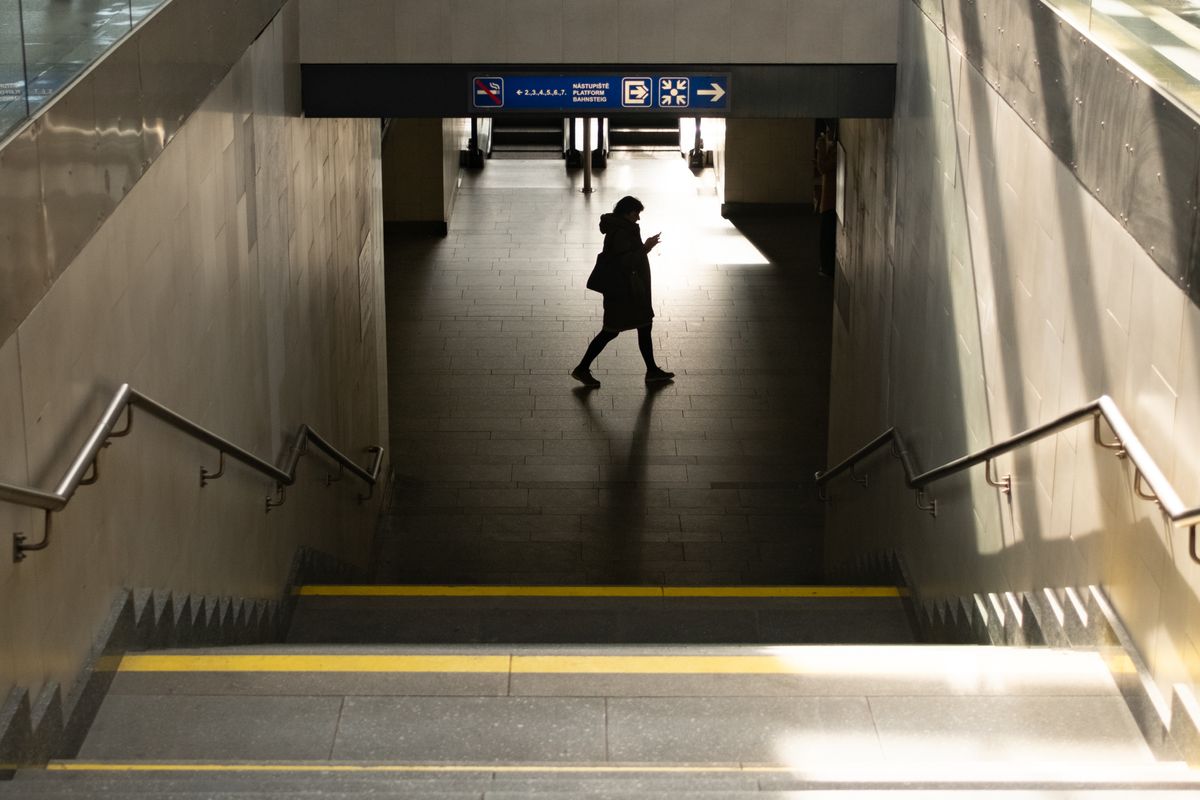 Person walking through a railway station in front of a beam of sunlight