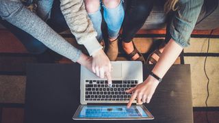 Group of people pointing at a website on a laptop