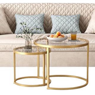 Two gold nesting tables in front of a white couch