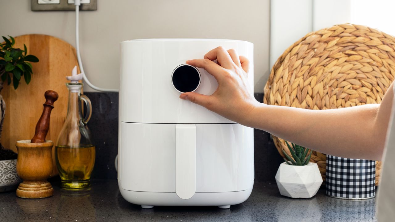 Person adjusting an air fryer&#039;s settings