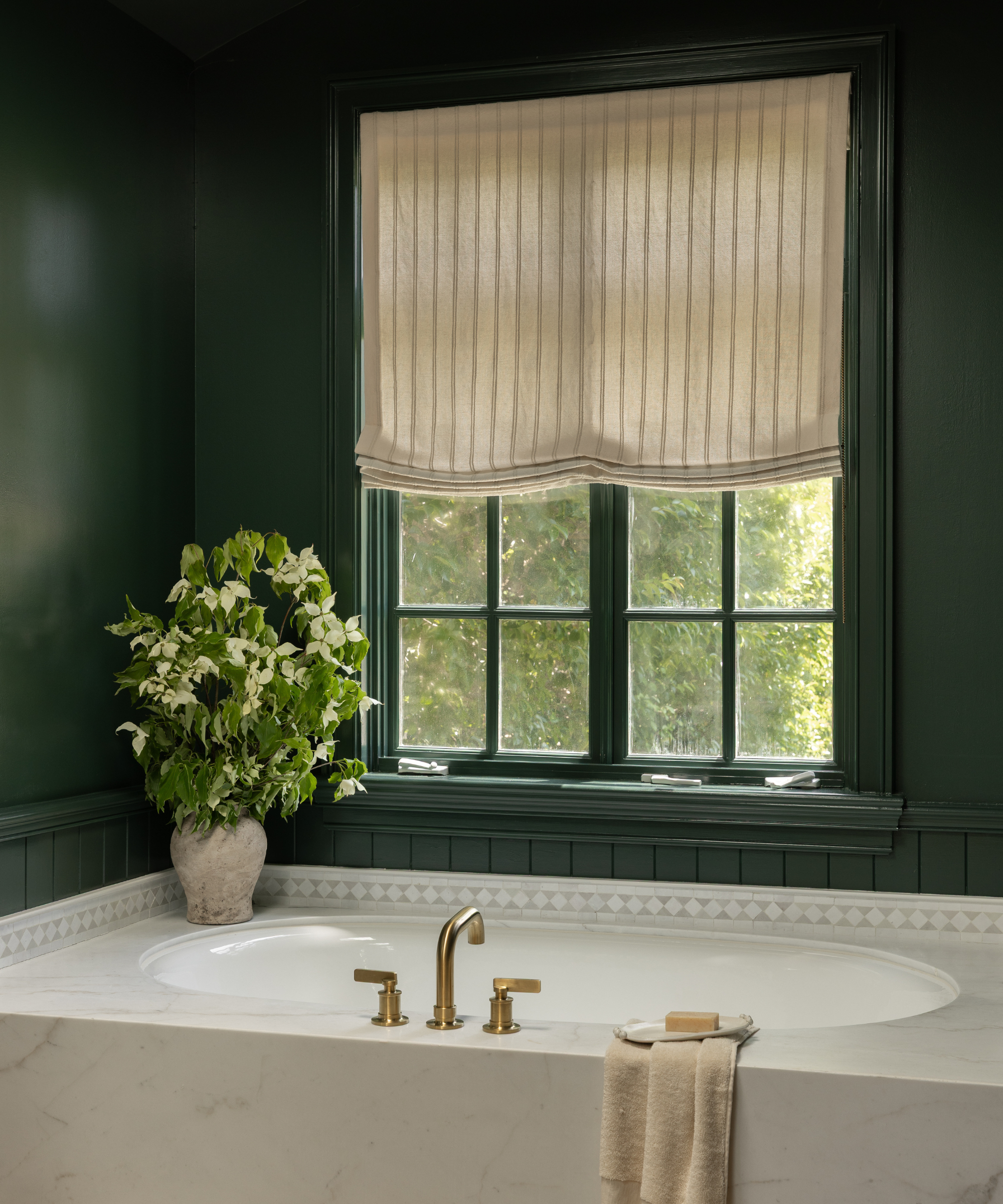 a bathtub in a green painted room with a curtain on the window