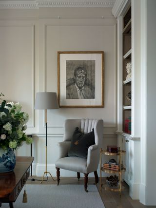 White shelving and original panelling on walls, grey armchair and lamp