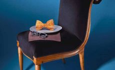 crab croquettes in the shape of an oversized bow tie displayed on blue velvet chair