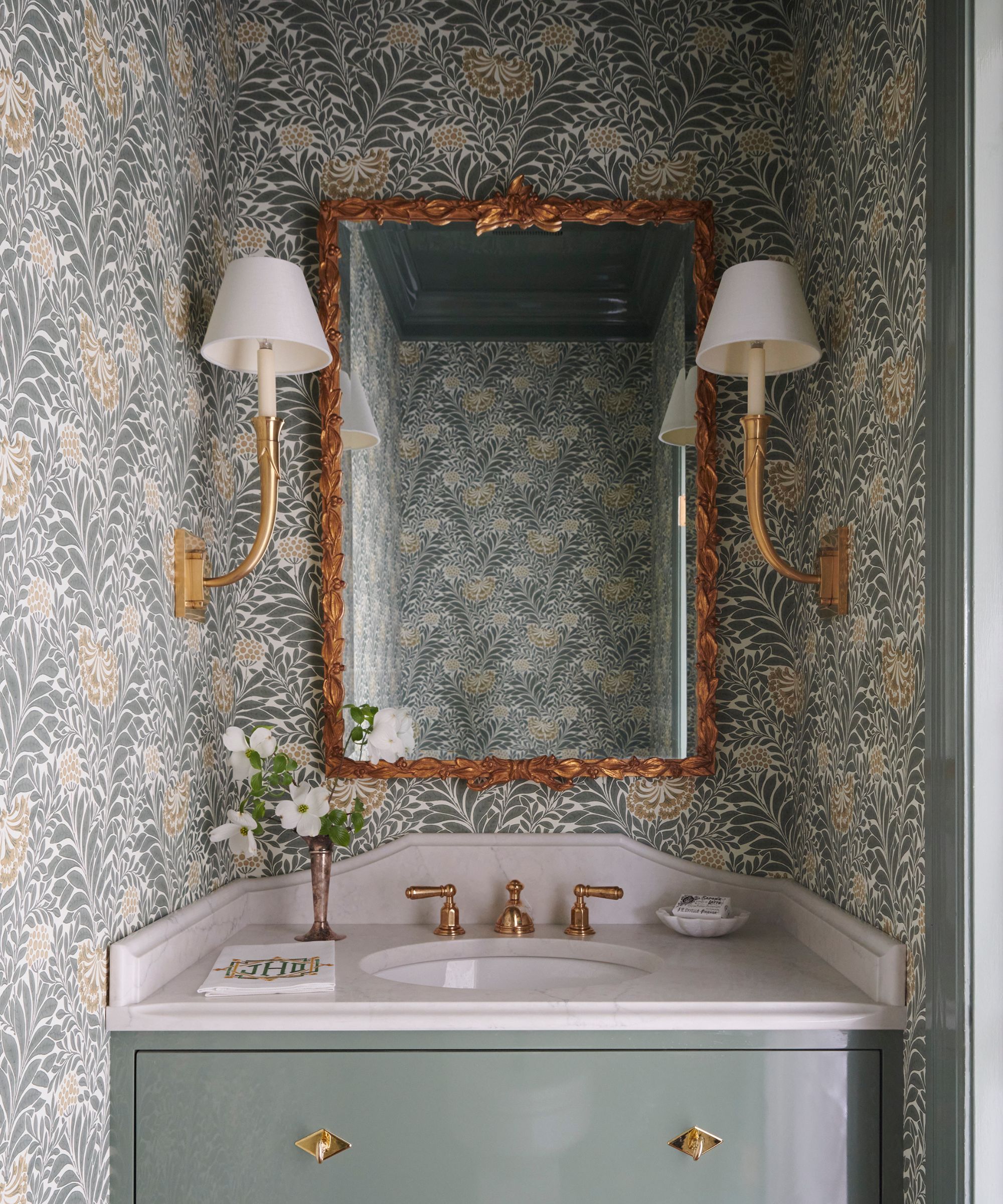 A Powder room vanity area with green floral wallpaper, green painted trim, and a vanity in the same green hue