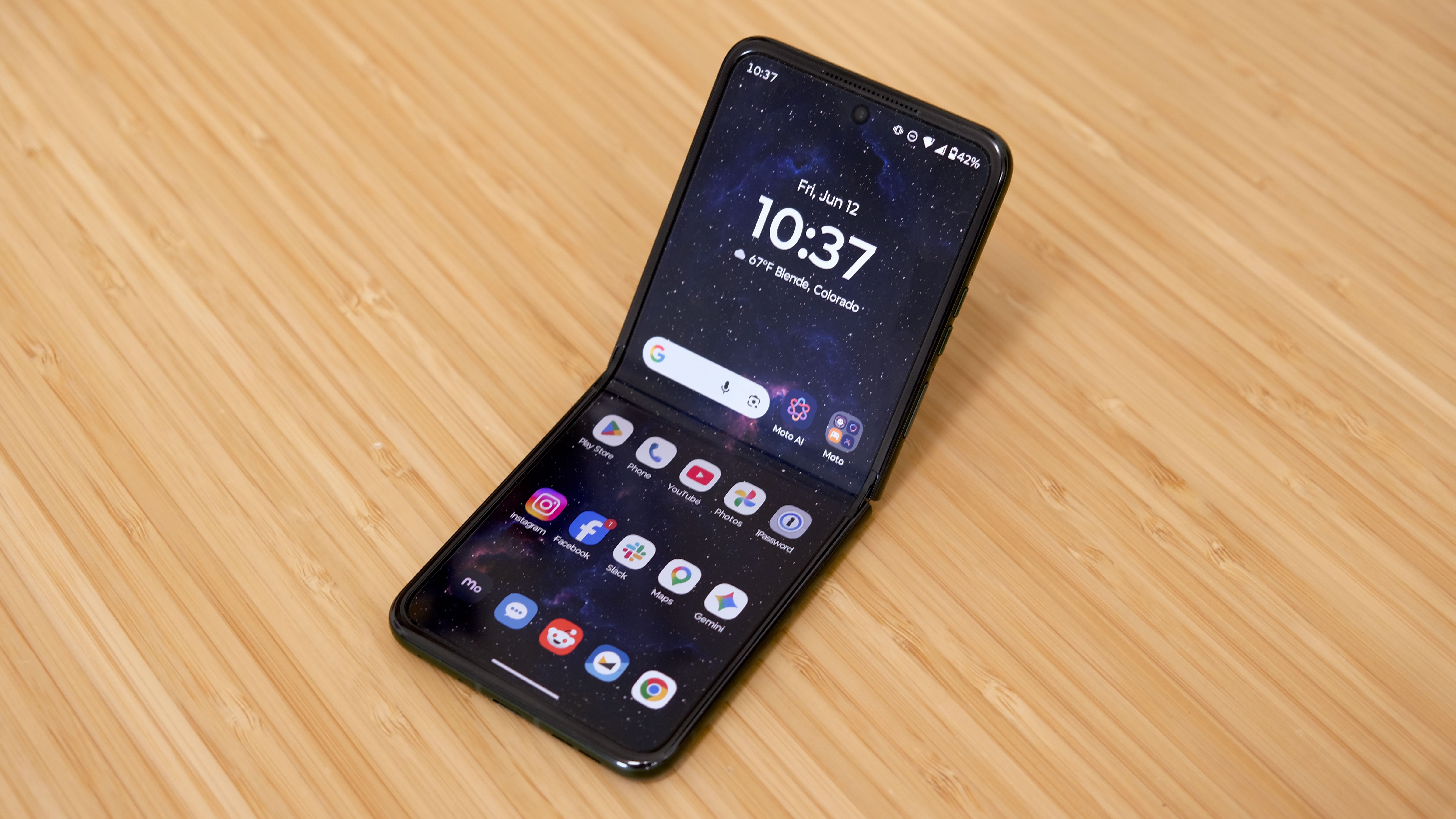 The Motorola Razr Plus 2026 in the hand and on a wooden table