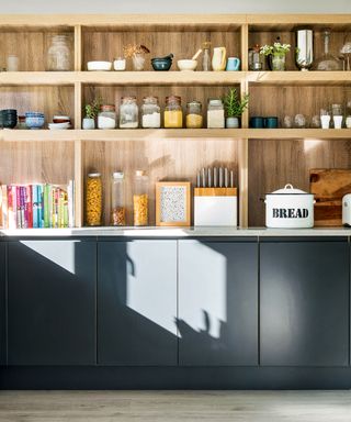 kitchen area with shelves on wall and marble worktop with dark grey cabinets