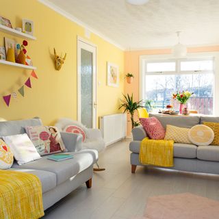 living room with multicolour wall and wooden and grey sofa set with multicolour coshions