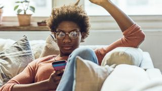 Connections news piece - woman looking at phone on couch