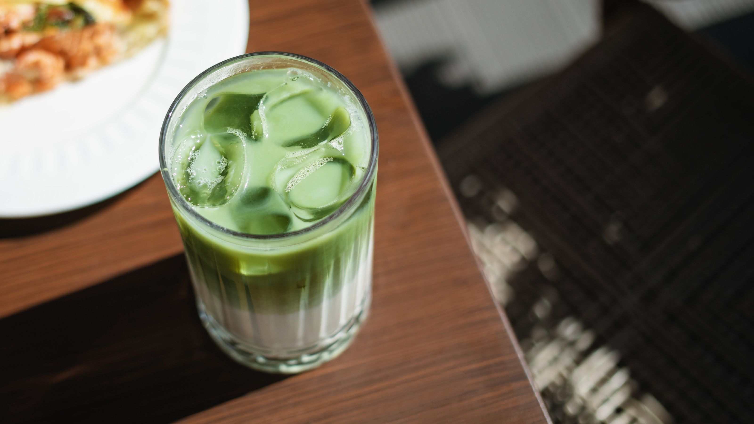 An iced matcha latte with cold foam on a wooden table, viewed from above. 