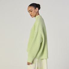 a model wears a green sweater and tie dye skirt from everlane