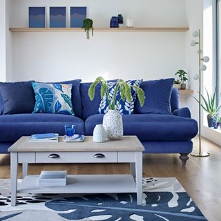 living room with blue sofaset with cushions and shelves on wall