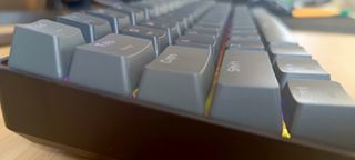 A grey Sablute SG KM61 keyboard sitting on a wooden desk