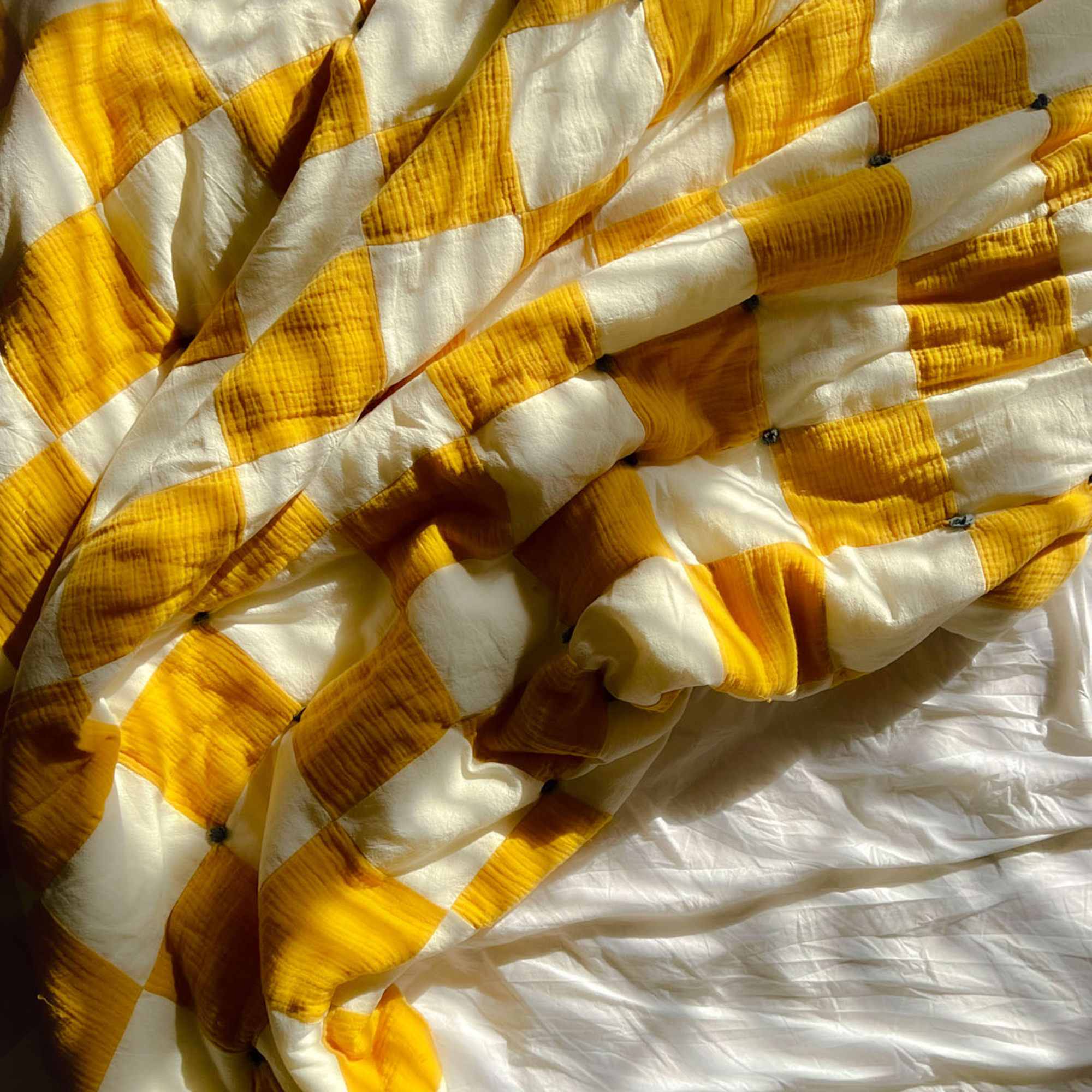yellow checked quilt messed up on a bed