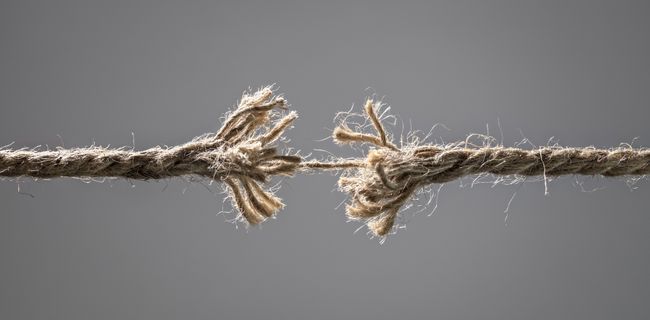 Frayed rope held together by a thread.