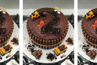 Close up of a chocolate cake covered in chocolate buttercream, the number two carved into the icing with a digger truck on top