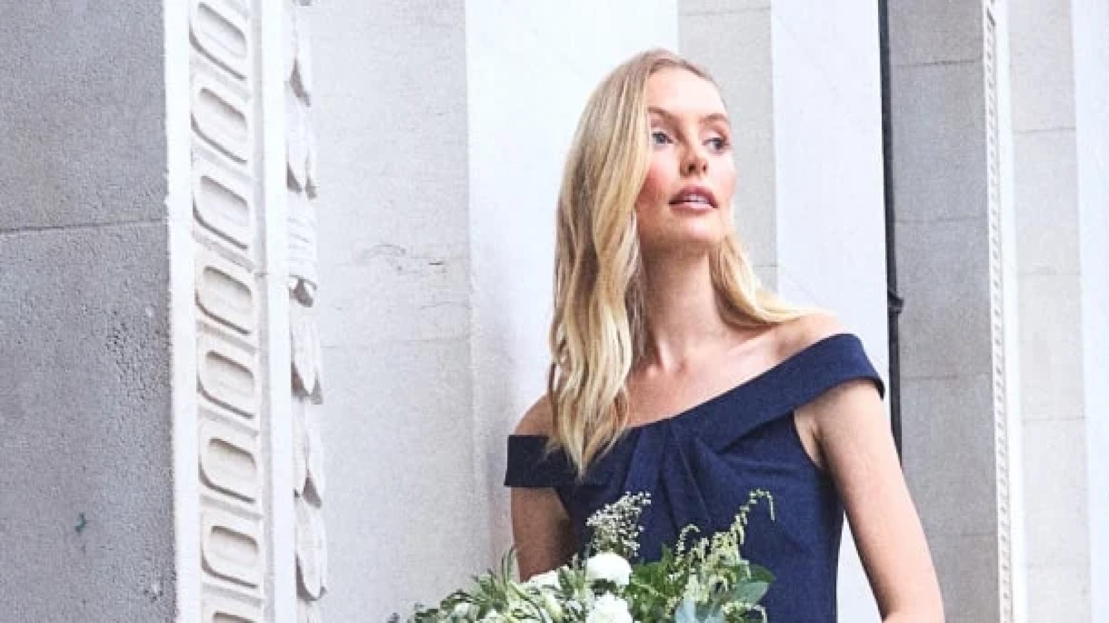 A woman in a dark blue dress holding flowers